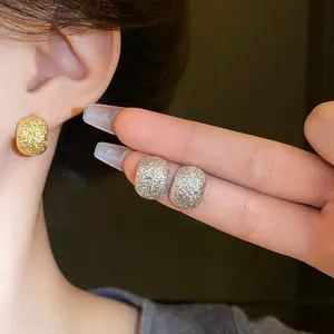 Detailed macro view of textured metallic bean stud earrings in gold and silver finish