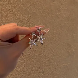 Close-up detail of elegant silver needle zircon star stud earrings held by hand