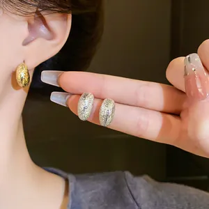 Detail shot of textured irregular bean stud earrings showing wearing effect and metallic finish