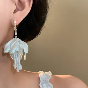 Close-up detail of elegant white flower earring with bead tassels on Asian model