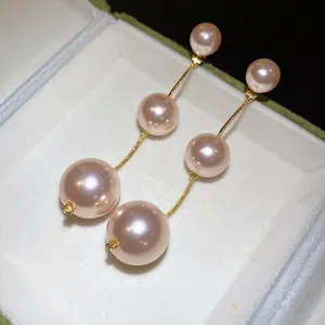 Close-up of elegant pink triple pearl drop earrings in a white jewelry gift box.