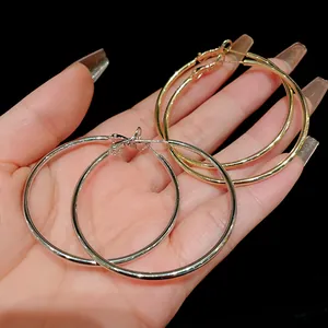 Pair of classic minimalist silver and gold metal hoop earrings held in hand for scale