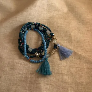 Close-up detail of Bohemian multi-layer beaded bracelet featuring blue tassels and wood beads