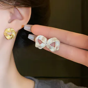 Detailed macro view of irregular textured metallic stud earrings in gold and silver finishes