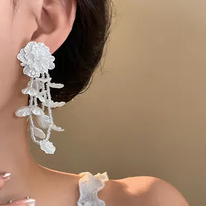 Detailed close-up of elegant white floral dangle earrings worn by a model for a stylish look