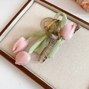 Macro detail of sweet tulip hair claw clip with pink fabric flowers and green ribbon