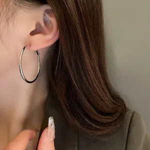 Close-up showing the elegant wearing effect of a minimalist large silver hoop earring