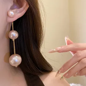 Macro view of elegant three-layered champagne pink pearl drop earrings for women