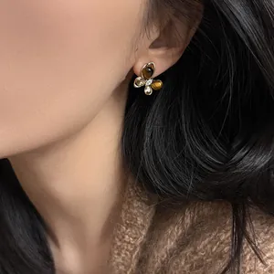 Elegant butterfly stud earrings with zircon and tiger eye stone inlay on model's ear
