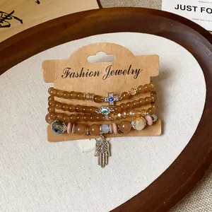 Detailed view of layered brown beaded bracelets with Hamsa hand and evil eye charms