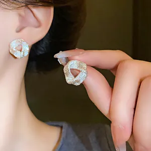 Close-up of textured irregular silver stud earrings showing intricate surface detail.