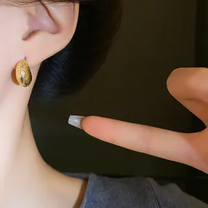 Detailed close-up view of gold irregular bean stud earrings featuring a textured metallic finish