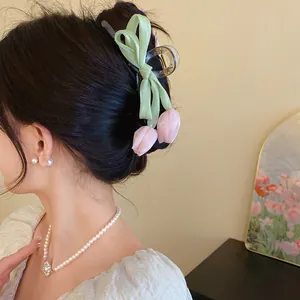 Detail view of sweet tulip hair claw clip with light green ribbon bow on model's hair