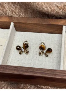 Close-up of butterfly stud earrings featuring faux tiger eye stones and sparkling zircon