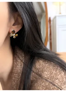 Detailed view of butterfly stud earring featuring tiger eye stones and zircon on person's ear