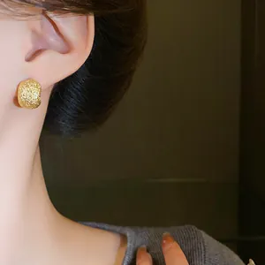 Elegant close-up of a gold textured irregular bean stud earring worn on a female ear