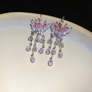 Primo piano di orecchini a farfalla in zircone rosa con nappe a goccia