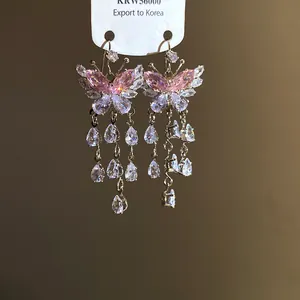 Primo piano di orecchini a farfalla in zirconia rosa e bianca con pendenti in cristallo.