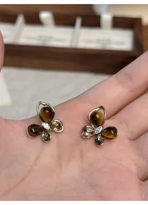 Detailed macro view of elegant butterfly stud earrings with imitation tiger eye stones