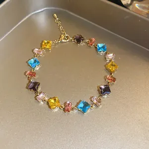 Close-up of elegant gold chain bracelet with vibrant colorful square zirconia stones