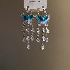 Dettaglio di orecchini a farfalla con scintillanti cristalli di zircone blu e trasparenti