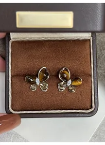 Close-up of elegant butterfly earrings with tiger eye stones in a brown gift box.