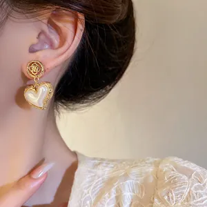 Close-up macro shot showing detailed pearl heart and flower earring on model ear