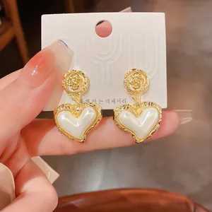 Detail of vintage baroque style gold heart earrings with white pearl-like inlay