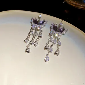 Primo piano di orecchini a farfalla in zircone con nappe a goccia scintillanti