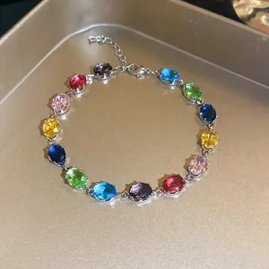 Close-up of a colorful oval zircon bracelet with sparkling gemstones on a gold tray