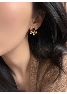 Close-up detail of a butterfly stud earring with zircon and tiger eye stone on model's ear.