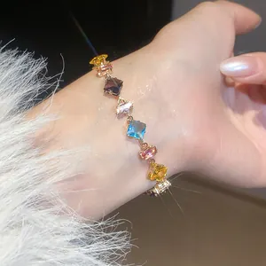 Detailed macro view of a colorful geometric zircon bracelet on a woman's wrist.