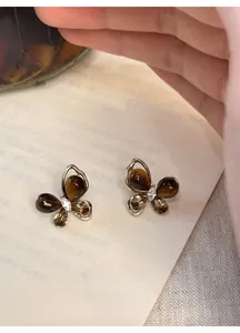 Detailed macro view of elegant butterfly stud earrings with tiger eye stone and zircon