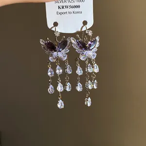 Dettaglio degli orecchini a farfalla in zircone con eleganti nappe a goccia d'acqua.