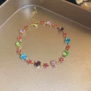 Detailed macro shot of a vibrant colorful heart-shaped zircon bracelet on a golden tray
