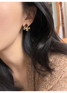 Close-up detail of elegant butterfly stud earrings featuring faux tiger eye stones on model's ear