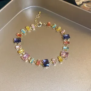 Detailed view of a gold-plated bracelet with colorful rectangular zircon stones on a tray