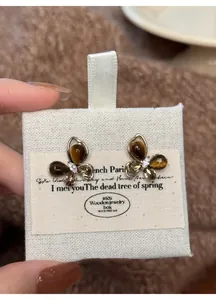Close-up of butterfly earrings with imitation tiger eye and zircon on a linen card