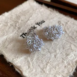 Détail macro de boucles d'oreilles élégantes en grappe de perles sur carte texturée