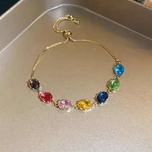 Detailed close-up of a gold-tone slider bracelet with vibrant multi-colored oval gemstones.