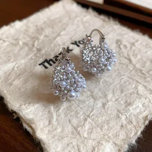 Gros plan de boucles d'oreilles créoles dorées 14 carats avec un amas de perles blanches