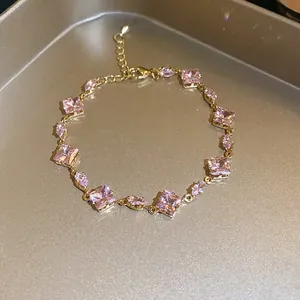Close-up of gold bracelet with sparkling pink square and marquise cubic zirconia.