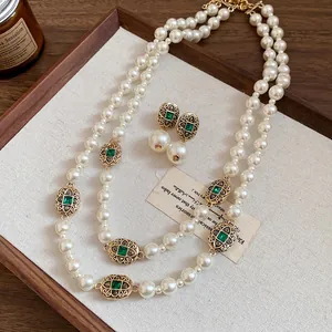 Vintage style pearl necklace and earring set with green gemstone details in wood tray