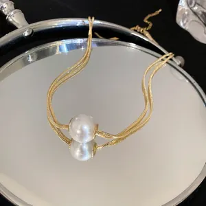 Close-up of elegant double-strand gold necklace with large white pearl pendant