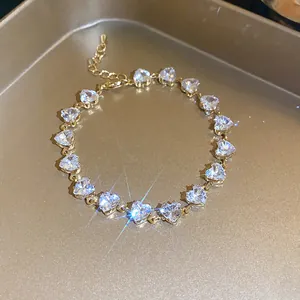 Detailed close-up of an elegant gold-tone bracelet featuring sparkling heart-shaped zircons