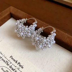 Gros plan de boucles d'oreilles créoles perles élégantes sur fond en tissu texturé rétro