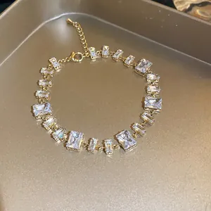 Close-up of gold-toned bracelet with sparkling emerald-cut clear zircons