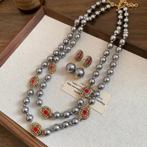Close-up of vintage grey pearl necklace and earring set with red rhinestone details