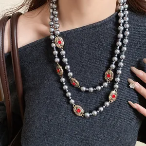 Detailed view of double-layer grey pearl necklace with vintage gold and red accents