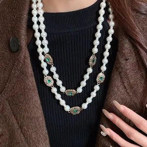 Close-up view of a double-layered vintage pearl necklace featuring retro emerald gemstone spacers